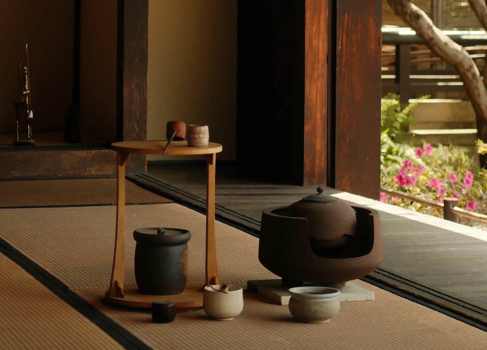 茶室に置かれた風炉と釜、茶碗。縁側の向こうに庭のつつじ